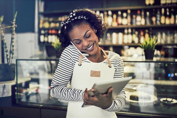 happy female restaurant manager on the phone while looking at her tablet