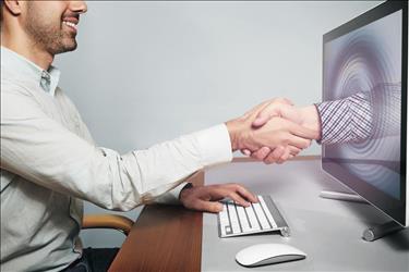 virtual onboarding/virtual handshake image concept with new hire shaking hands with his new manager through a computer screen