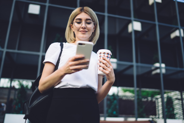 employee looking at phone and holding a cup of coffee