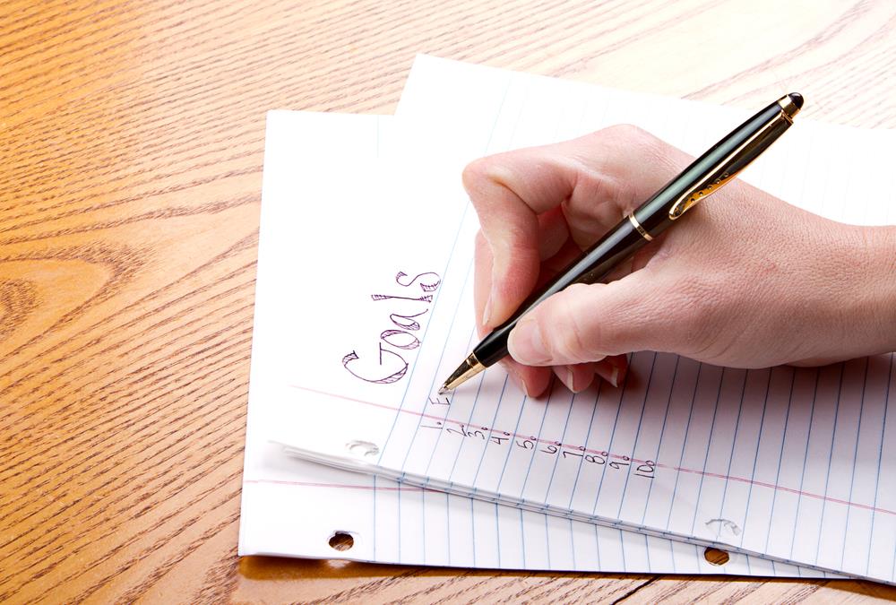 close up of a hand writing down goals