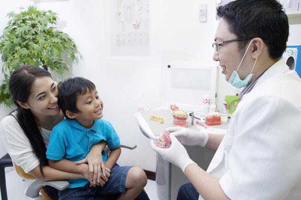 Community dental health coordinator educating mother and child on proper dental hygiene