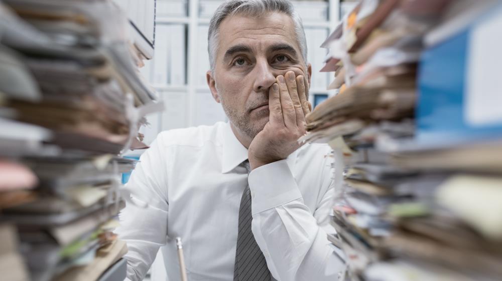 Exhausted business man sitting among piles of work