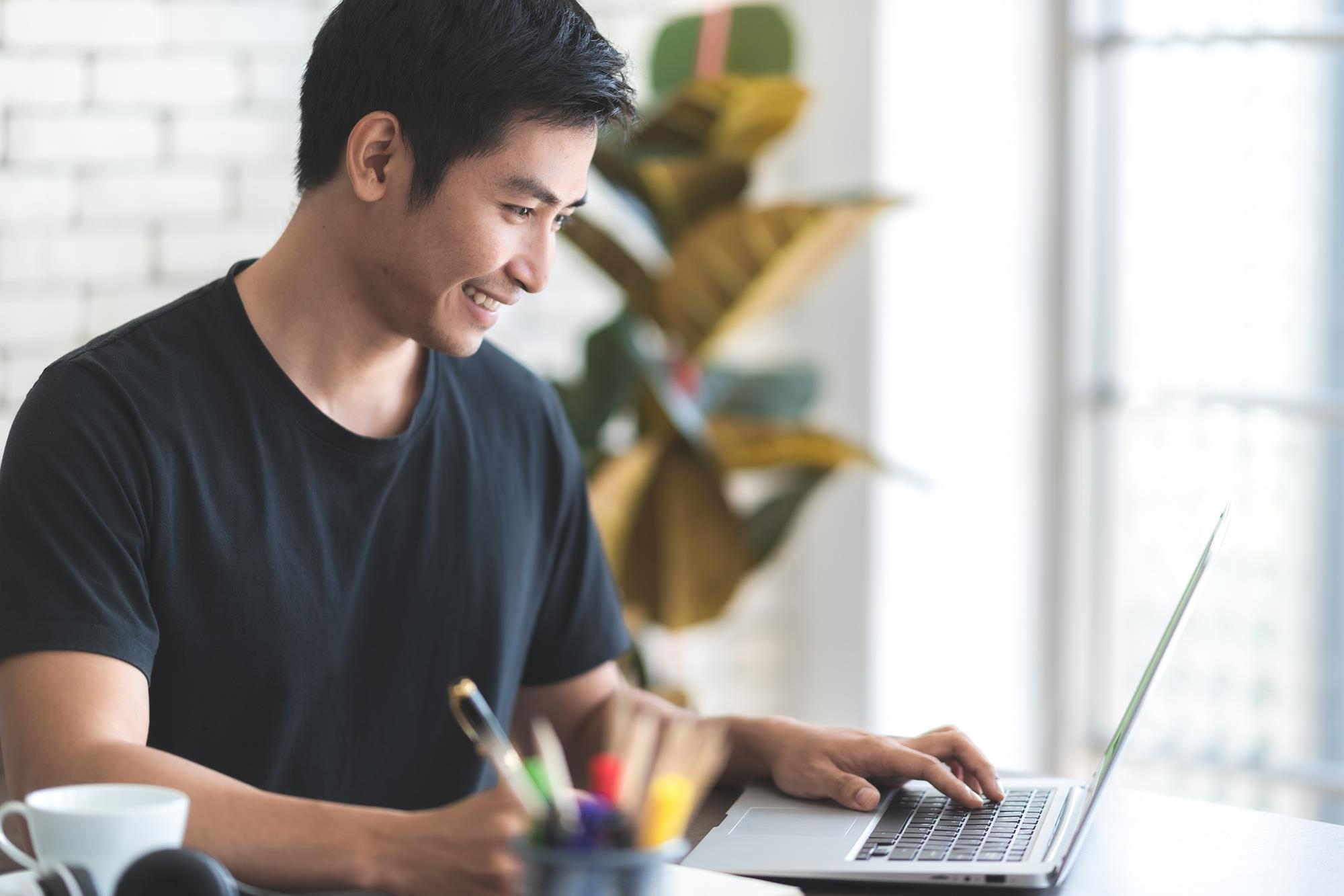freelancer smiling while working from home on his laptop
