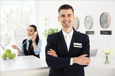 hospitality worker by a front desk smiling