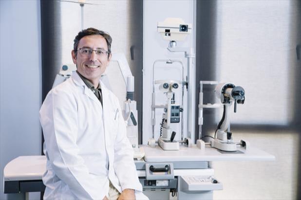 Ophthalmology physician assistant sitting in front of various equipment used in eye care