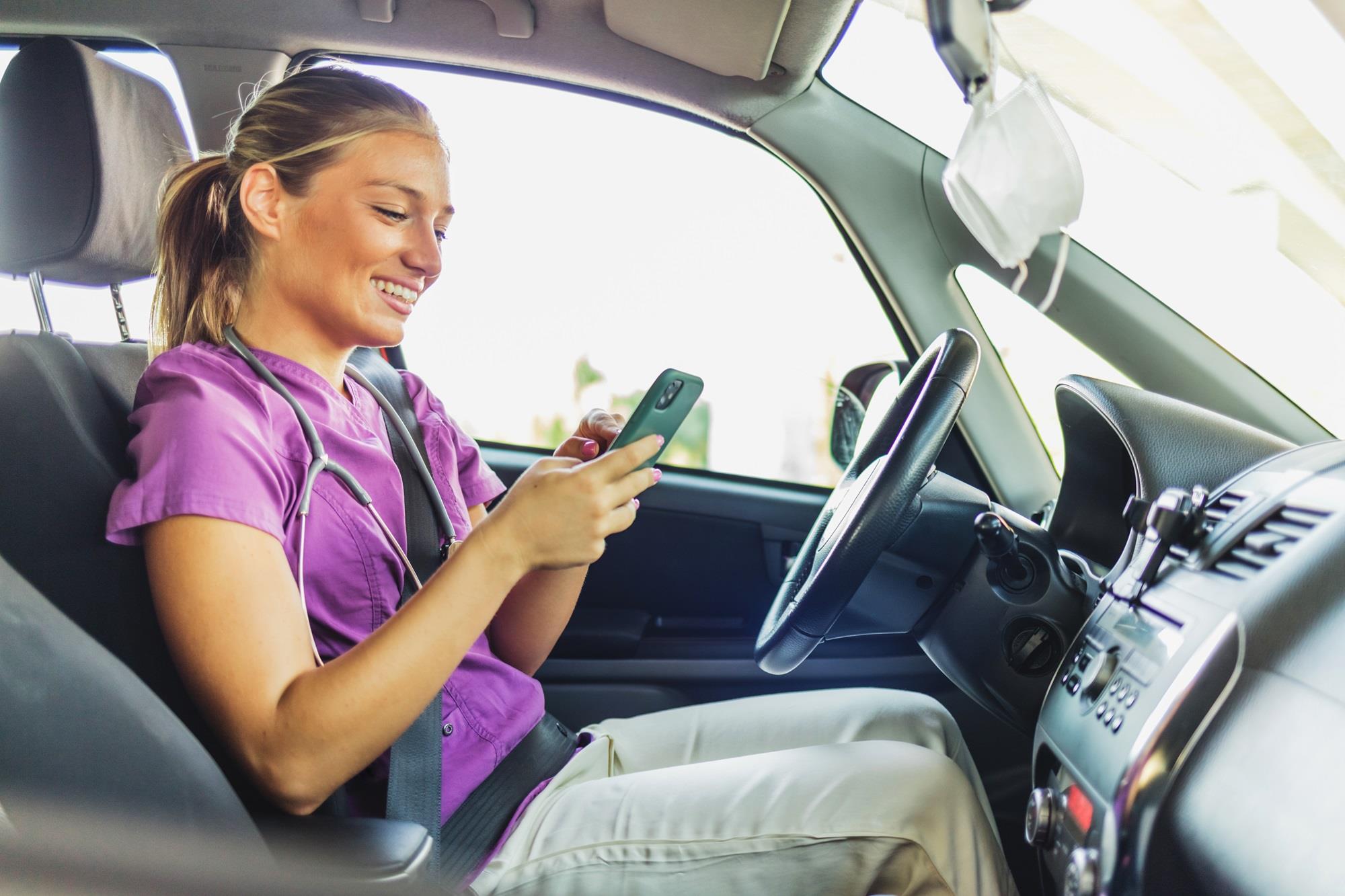 nurse in her car sending a message on her phone