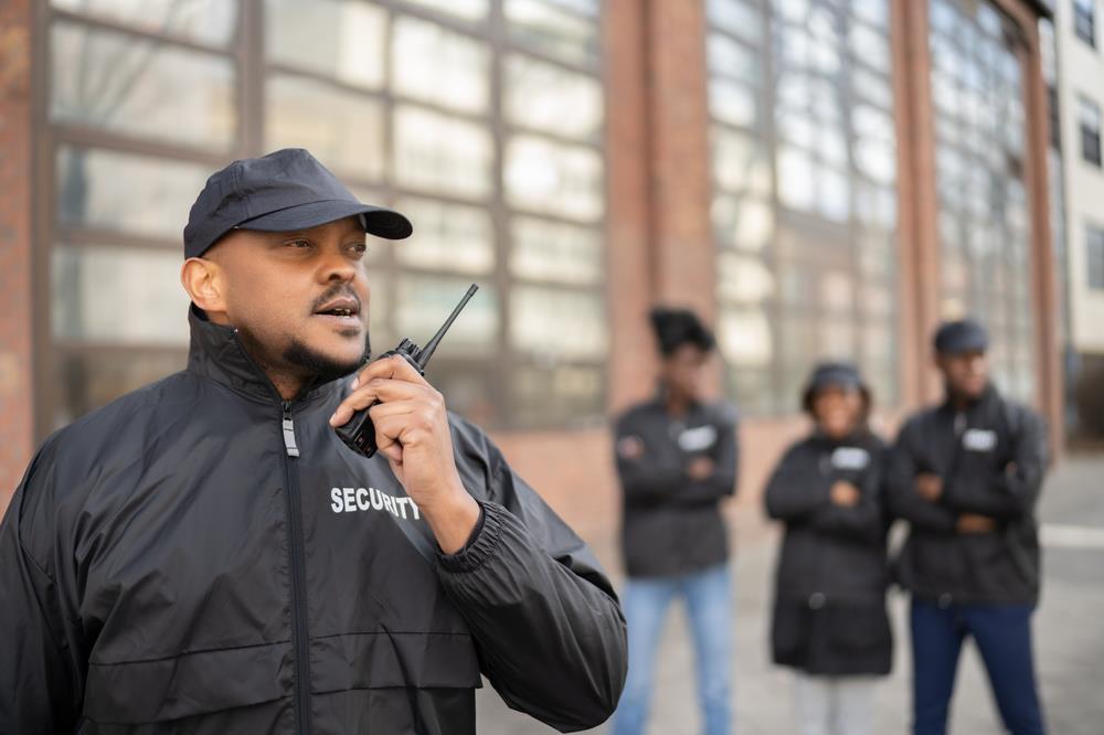 security guard using a walkie talkie with his team in the background