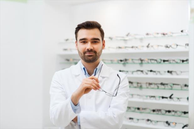 Optician standing in front of shelves with frames