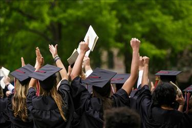 New college graduates in robes throwing their hands in the air