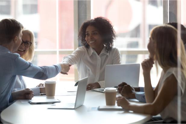 employees shaking hands at a conference table