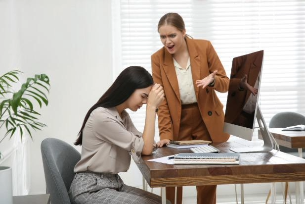 frustrated employee at desk getting yelled at by boss