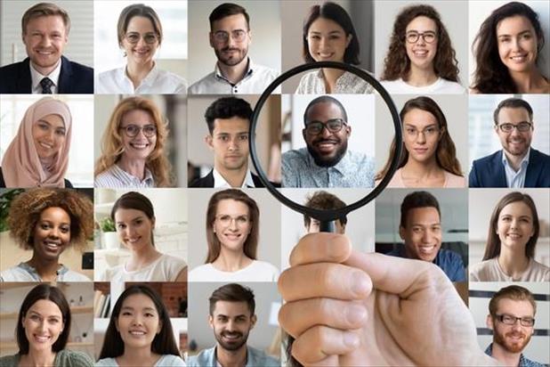 Recruiter holding up a magnifying glass to the right candidates amongst a panel of job seeker photos 