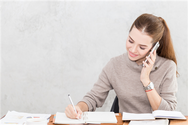 business woman on the phone while writing notes