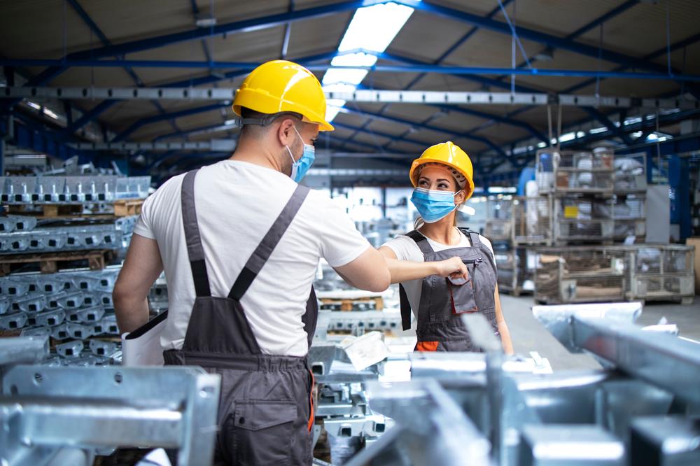 Friendly colleagues in a factory bumping elbows