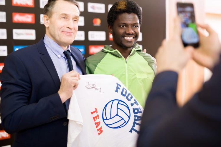 agent and athlete posing with signed t-shirt