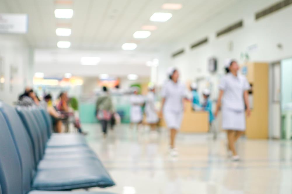 View of hospital waiting area with two nurses walking in the background.