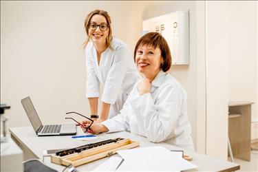 Smiling optometrist and optometric assistant posing inside their practice