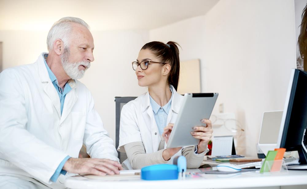 Optometrist having a discussion with optometry assistant at her desk