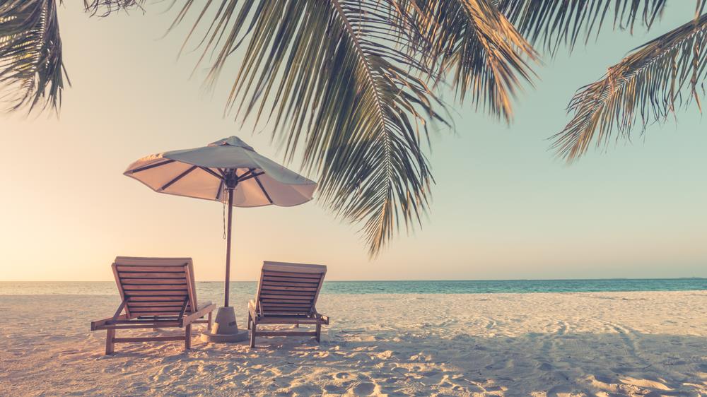 empty beach with two beach chairs and an umbrella