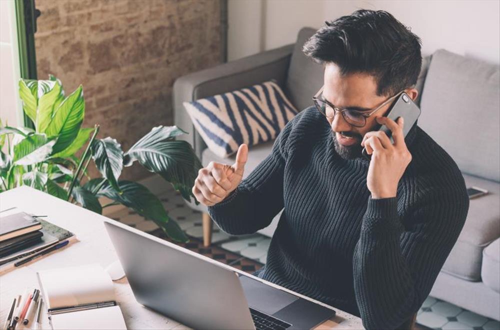 Man talking on phone at laptop