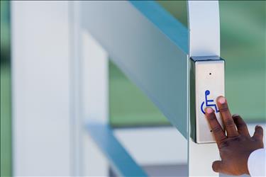 Person using the automatic door button to enter a building