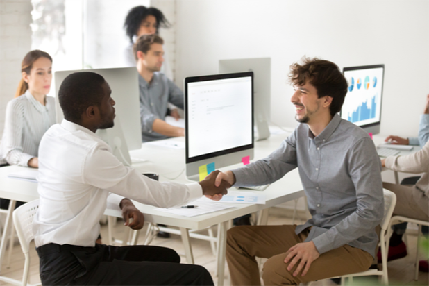 New hire shaking hands with coworker as part of onboarding process