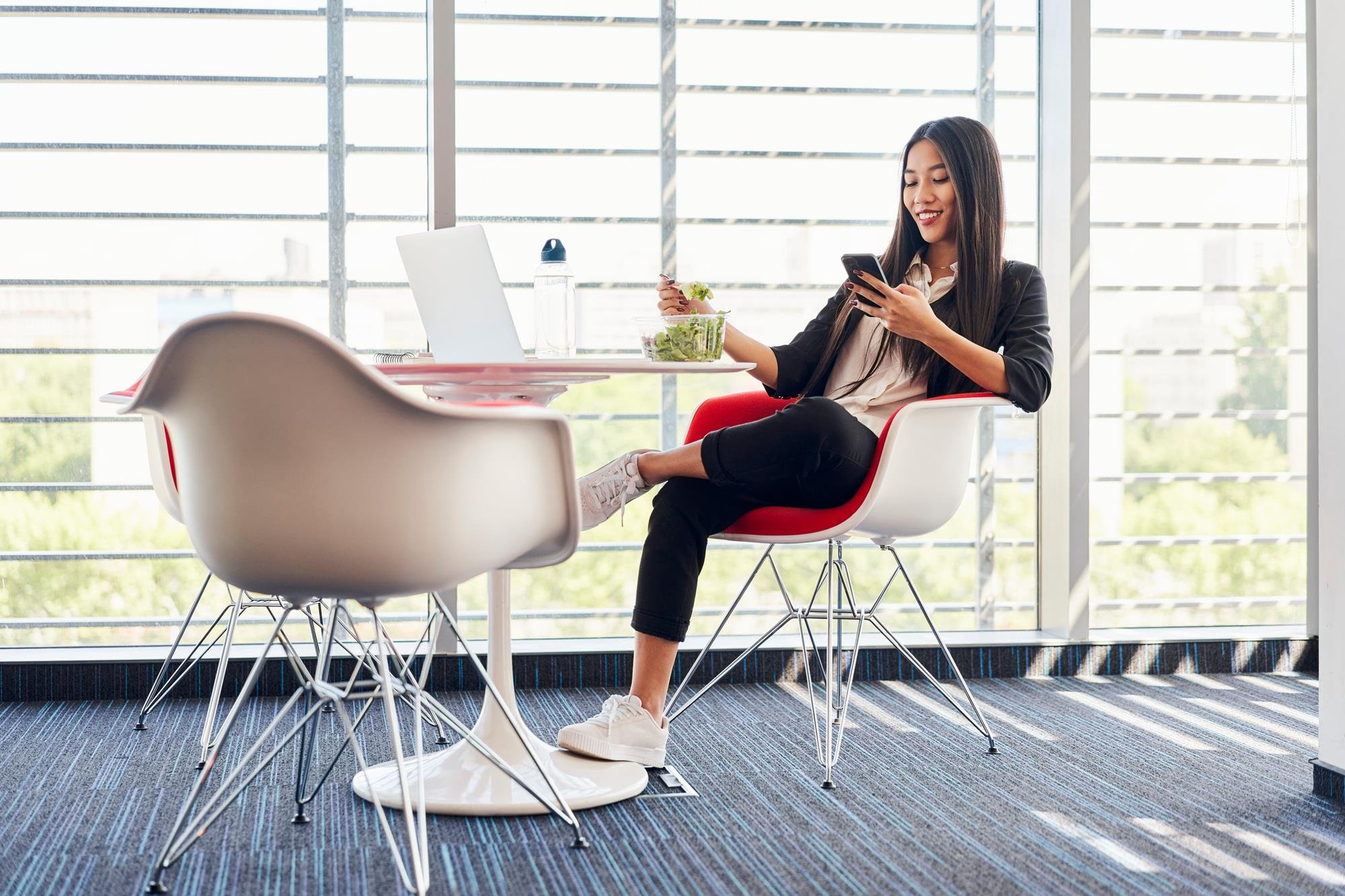 freelancer catching up on emails on her phone during lunch