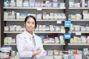 Pharmacist posing in front of shelves full of medications