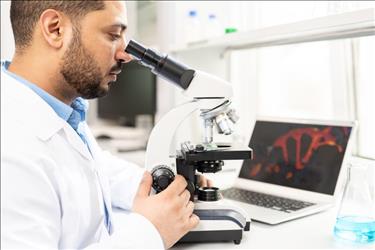 microbiologist studying a sample on a microscope