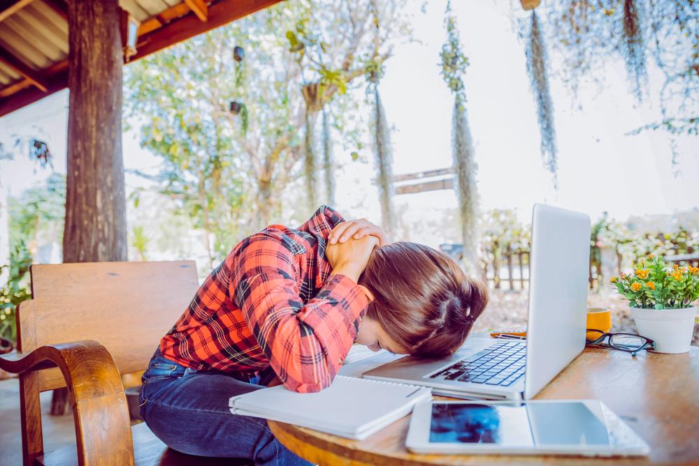 Stressed manager resting head on laptop