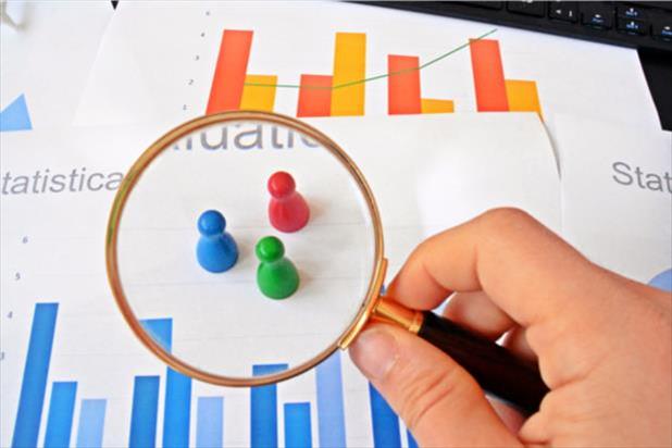 magnifying glass looking at statistics on paper