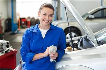 Woman mechanic leaning against car