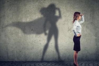 Professionally dressed job seeker stands proudly with her shadow in the background wearing a superhero cape.