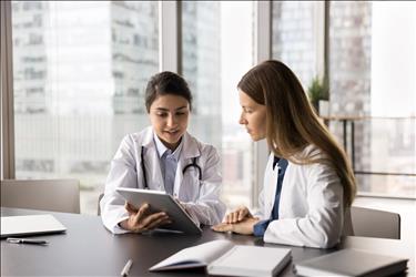 two medical professionals looking at a tablet together