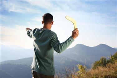 man throwing a boomerang with mountains in the background