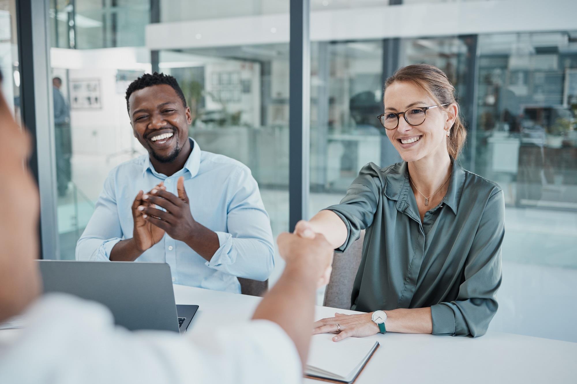 new hire shaking hands with her new team member while another one celebrates