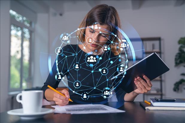 woman working at a table with digital social networking images overlaid