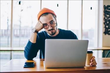 Man cringing at his computer after making mistake