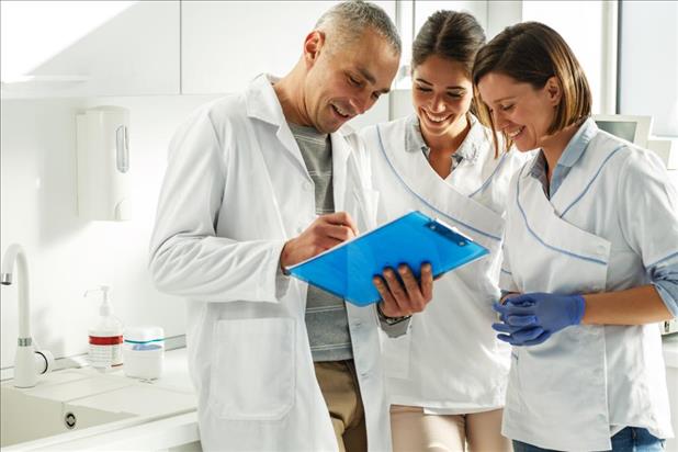 three dental team members smiling while looking at files