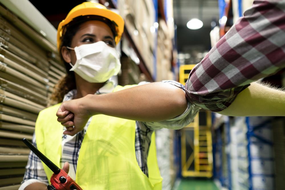 Happy employee with a mask elbow bumping boss