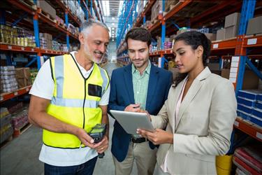 logistics manager reviewing data with her team in the warehouse