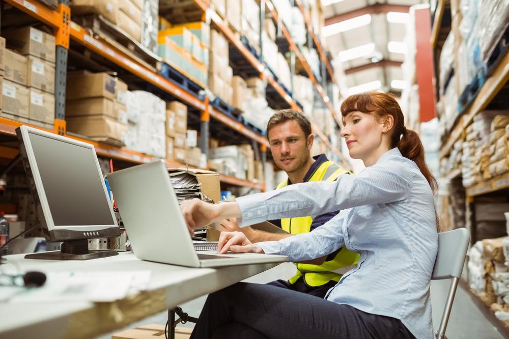 logistics business systems analyst reviewing data with a warehouse team member