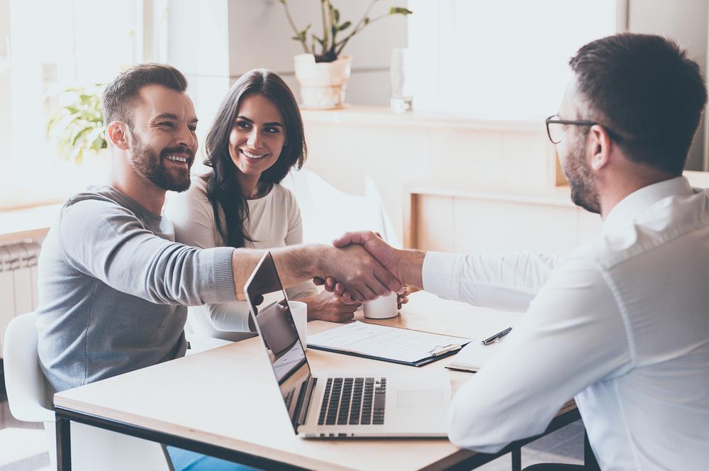 insurance agent shaking hands with a client after assisting a couple with their insurance needs