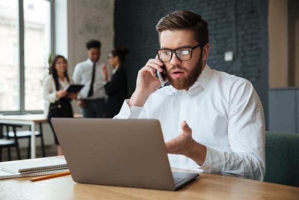 man looking at computer while talking on the phone