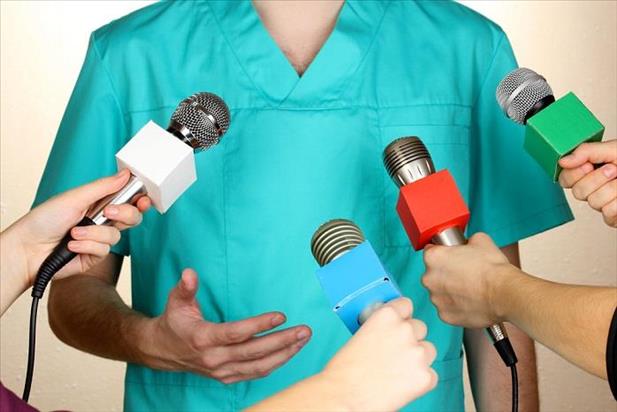 Medical professional standing in front of several microphones and answering difficult questions