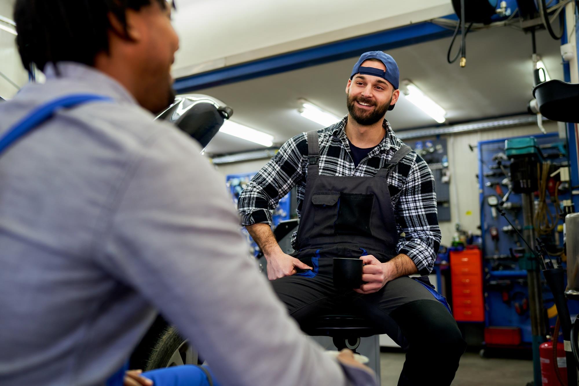 two auto mechanics talking during their break