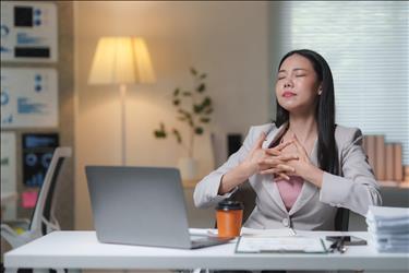 office worker meditating at her desk with her eyes closed