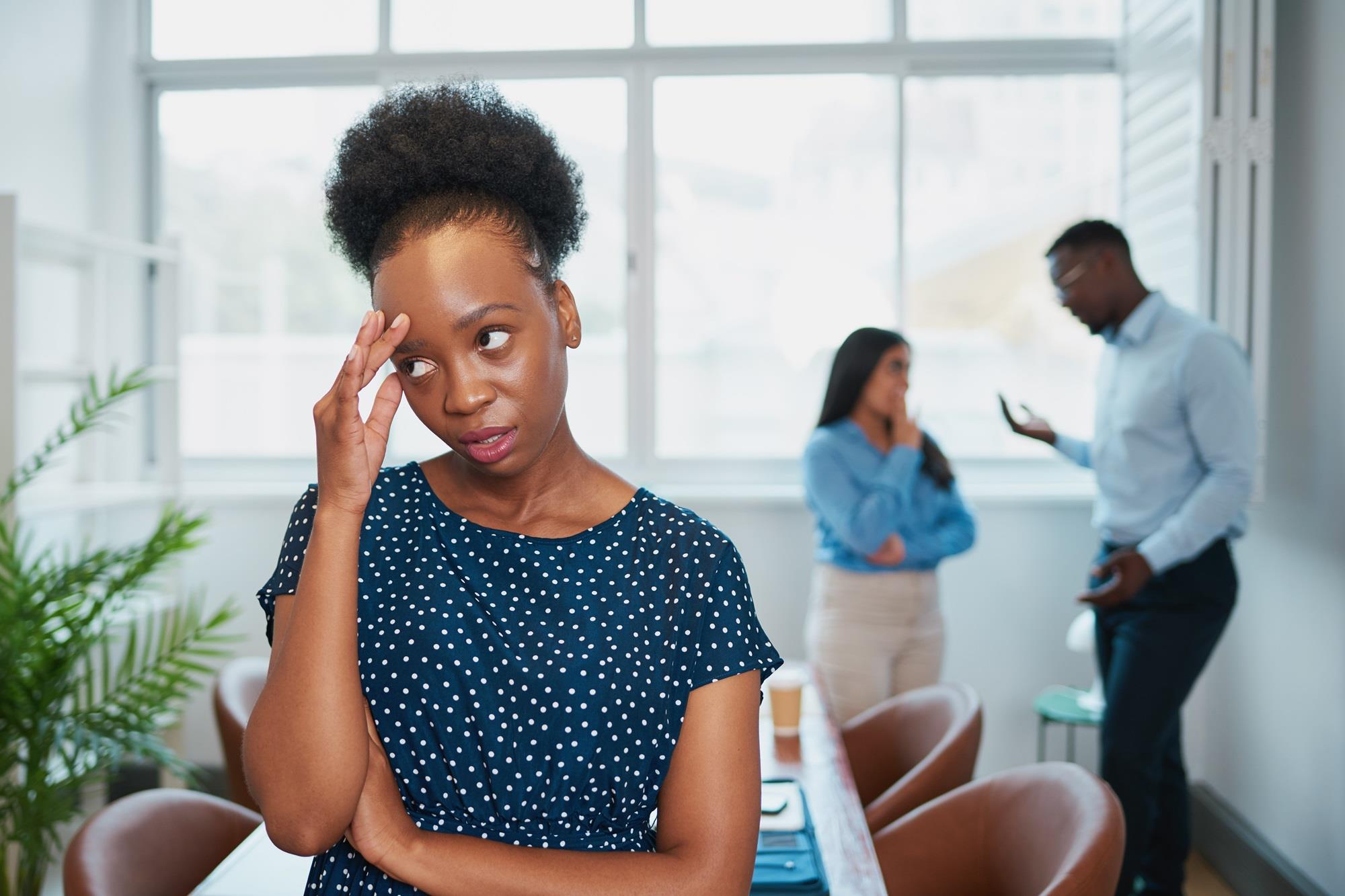 annoyed employee listening to her coworkers gossip behind her