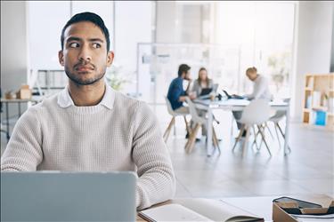 employee looking concerned as he listens to his coworkers gossip behind him