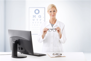 Happy hospital optometrist posing for camera with pair of eyeglasses